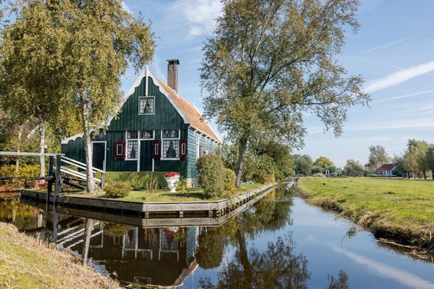 Et grønt hus med rødt tag ved en stille flod. 3