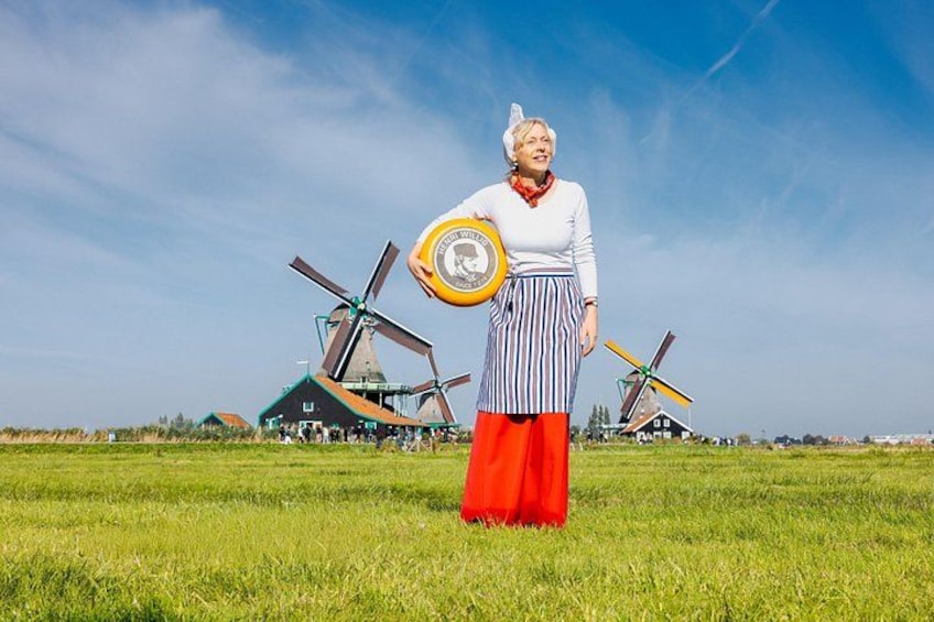 A person in traditional attire standing in a field with windmills in the background. 2