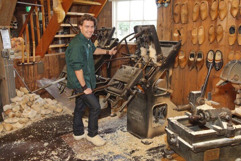 A person working with a shoe-making machine in a workshop with wooden walls and various tools. 2