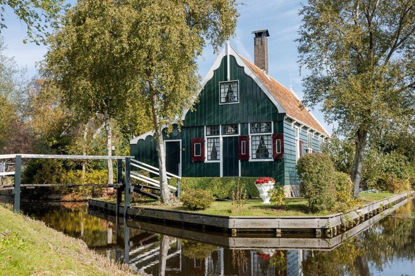 A green house with a red door, a small dock, and a calm water body. 4