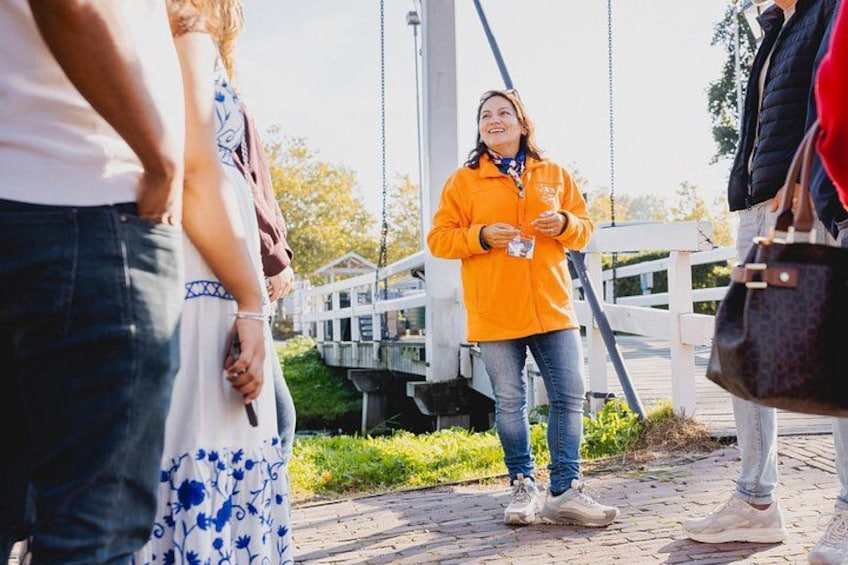 En person i en orange jakke står på en bro med et hvidt hegn i baggrunden. 4