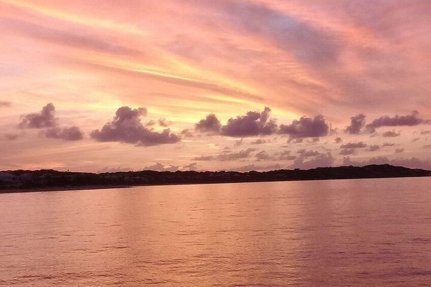 A sunset over a calm body of water with a distant shoreline. 3