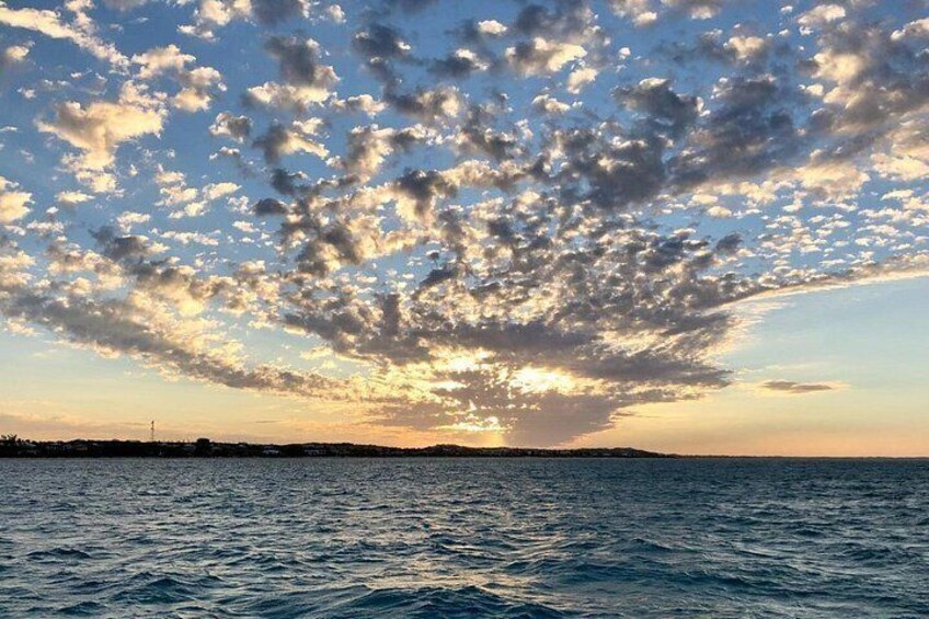 A sunset over a body of water with scattered clouds. 2