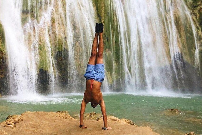 Una persona haciendo una parada de manos al pie de una cascada. 1