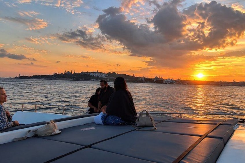 A sunset over a body of water with a boat and people on it. 3
