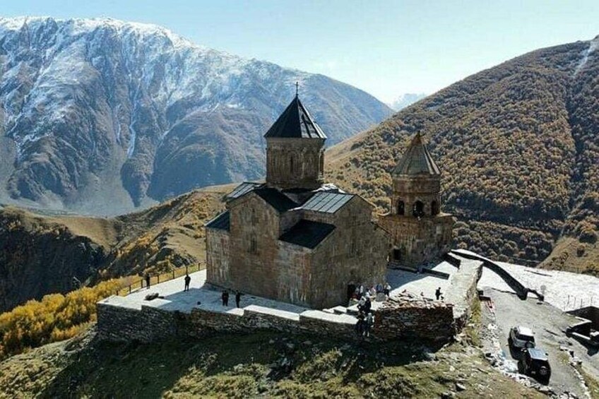 Een stenen kerk met een klokkentoren, voor een bergachtig landschap. 5