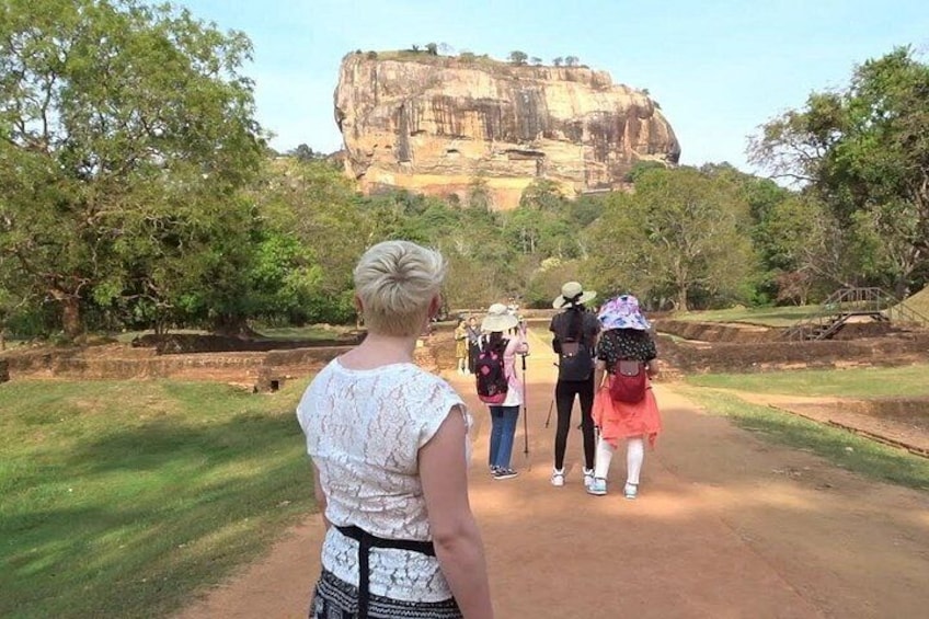 A group of people walking on a path towards a large rock formation. 3