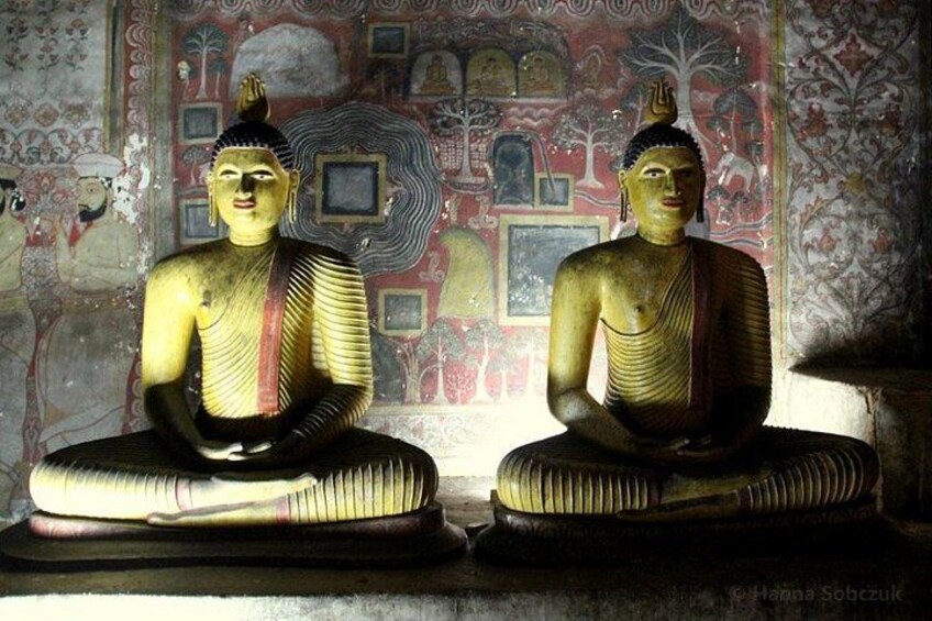 Two golden Buddha statues with intricate patterns, set against a detailed mural background. 2
