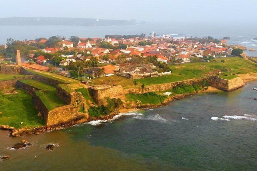A coastal town with a fortified structure, a lighthouse, and a harbor. 2