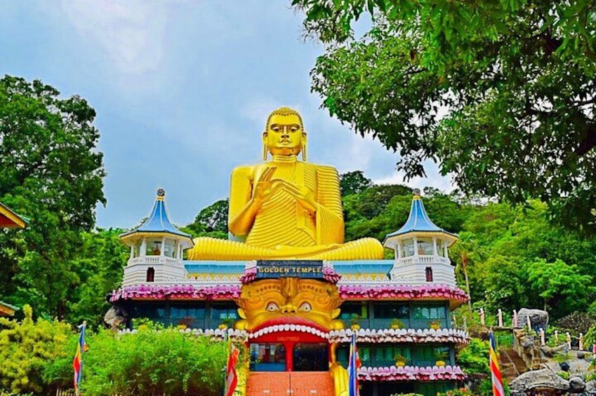 En stor gylden Buddha-statue, et tempel med blå tag og frodige grønne træer. 2