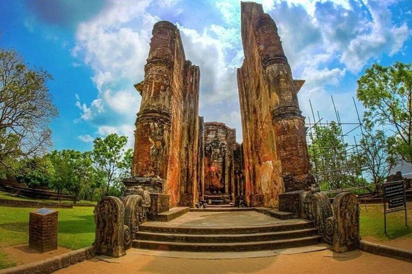 Ancient stone structures with steps leading up to them, surrounded by trees and a clear sky. 1