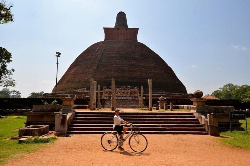 A large, domed structure with steps leading up to it, a person on a bicycle, and a clear sky. 3