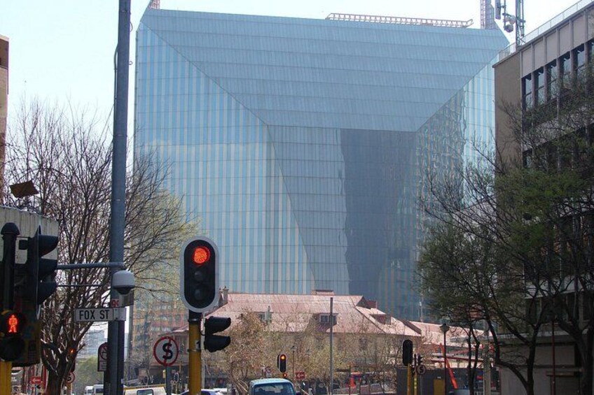 Un bâtiment moderne en verre, des feux de signalisation et une rue bordée de voitures et d’arbres. 3