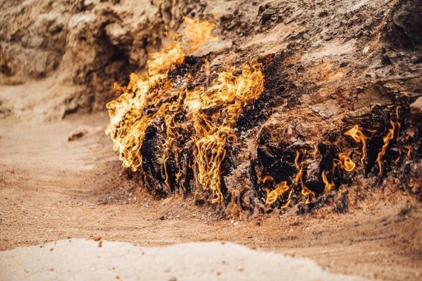 A fire burning on a log in a dry, sandy area. 5