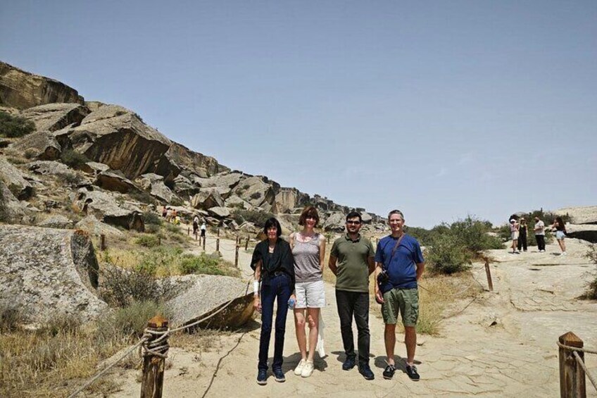 A group of people standing on a rocky trail with large boulders and sparse vegetation. 3