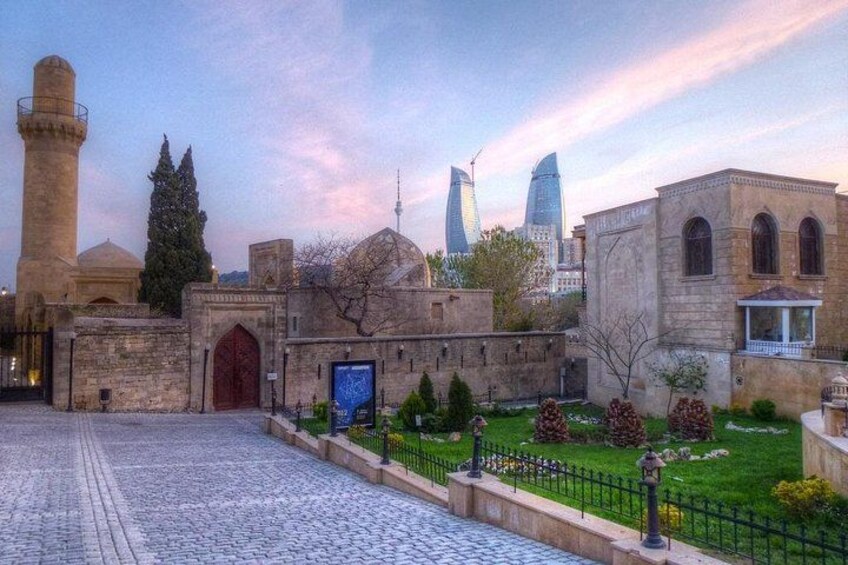 A historic building with a minaret, a modern skyscraper, and a well-maintained garden. 1