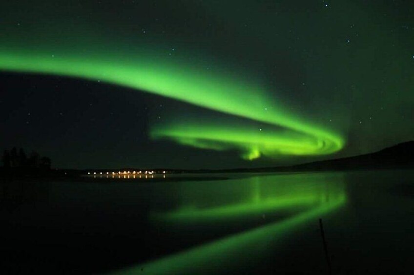 The Northern Lights over a calm lake with a distant shoreline. 4