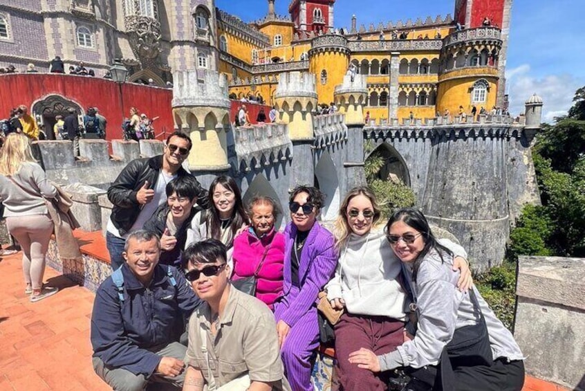 A group of people posing in front of a historic building with ornate architecture. 2