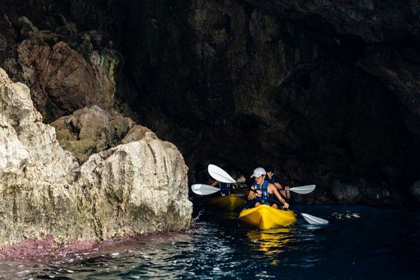 Two kayakers in a narrow water passage surrounded by rocky cliffs. 3
