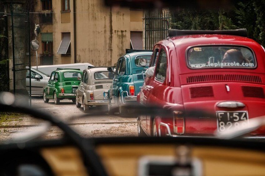A street with parked cars, including a red car with a visible license plate. 1
