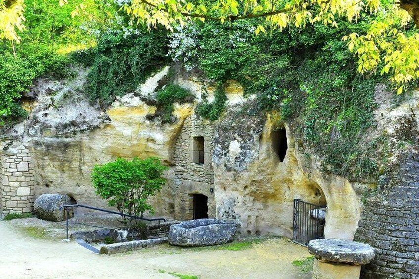 A cave-like structure with multiple openings, stone benches, and a small tree. 3