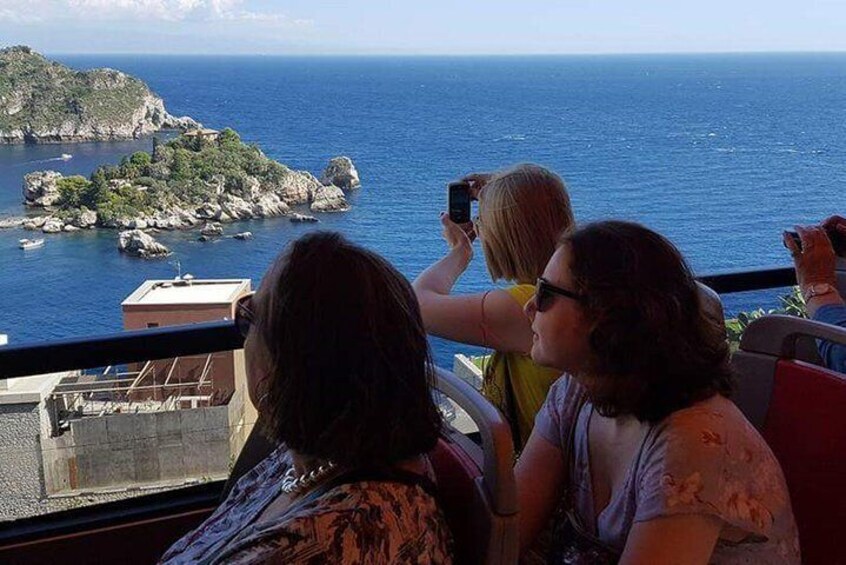 People on a balcony overlooking a coastal view with rocky islands and the sea. 2