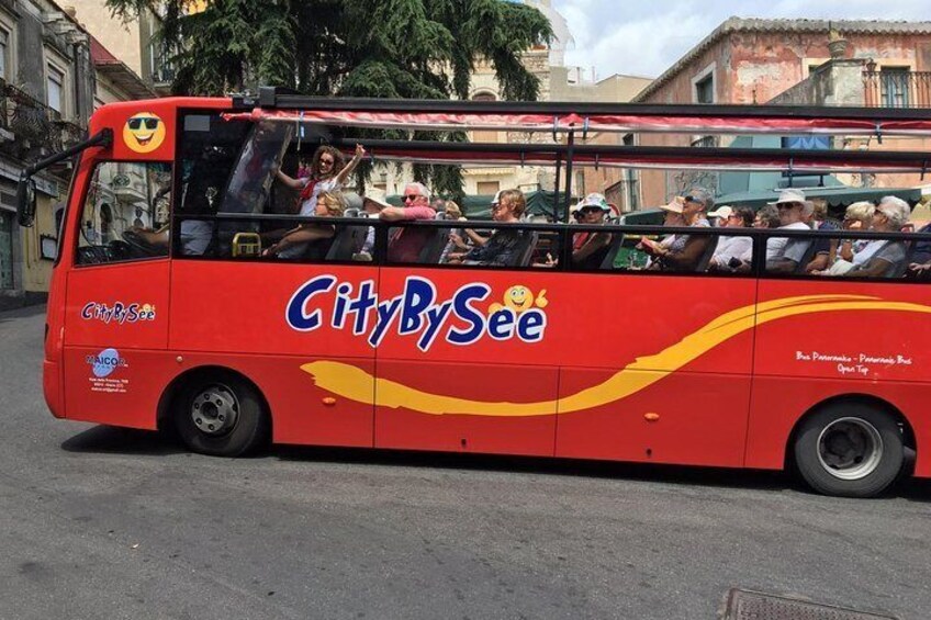 A red CityBySee bus with passengers, parked on a street. 1