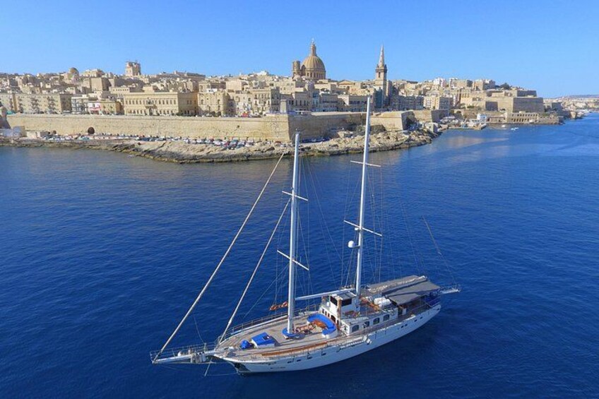 A sailboat on calm waters with a historic cityscape in the background. 3