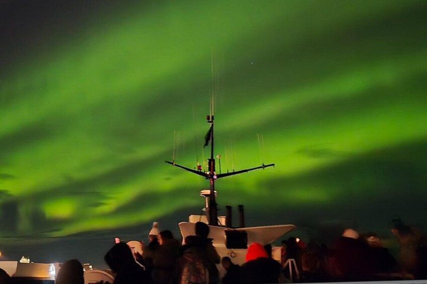 Et skib med mast og antenne, en menneskemængde og nordlys i baggrunden. 2