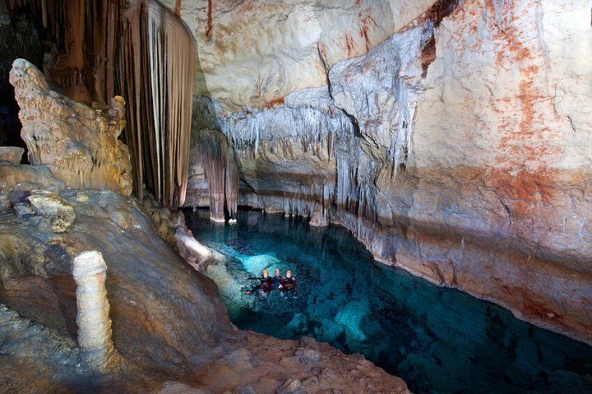 A cave with stalactites, a water pool, and a person kayaking. 1