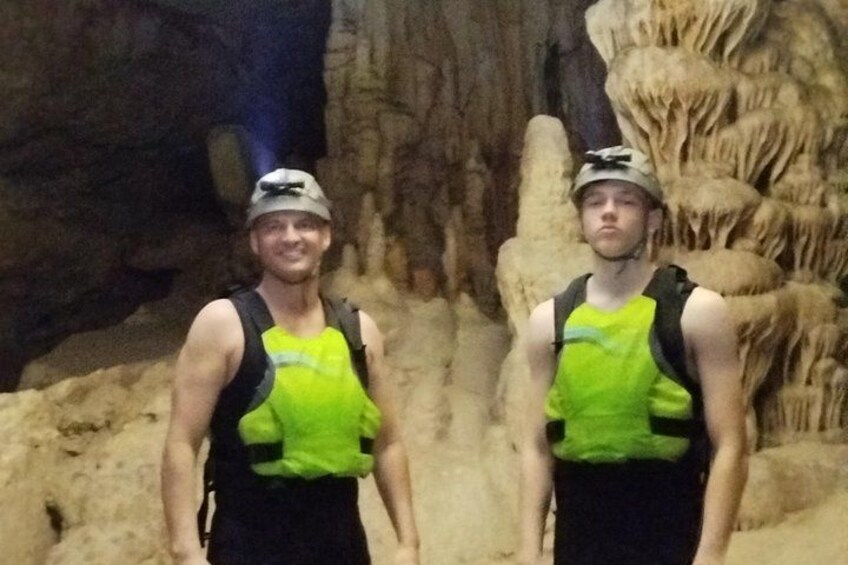 Two people wearing safety vests and helmets in a cave with stalactites. 2