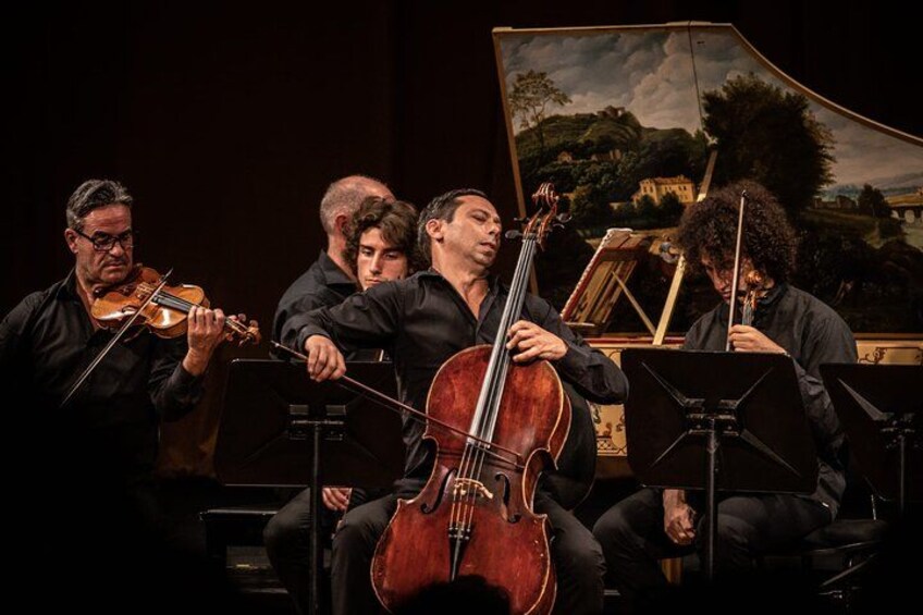 A string quartet performing on stage with a backdrop of a landscape painting. 5
