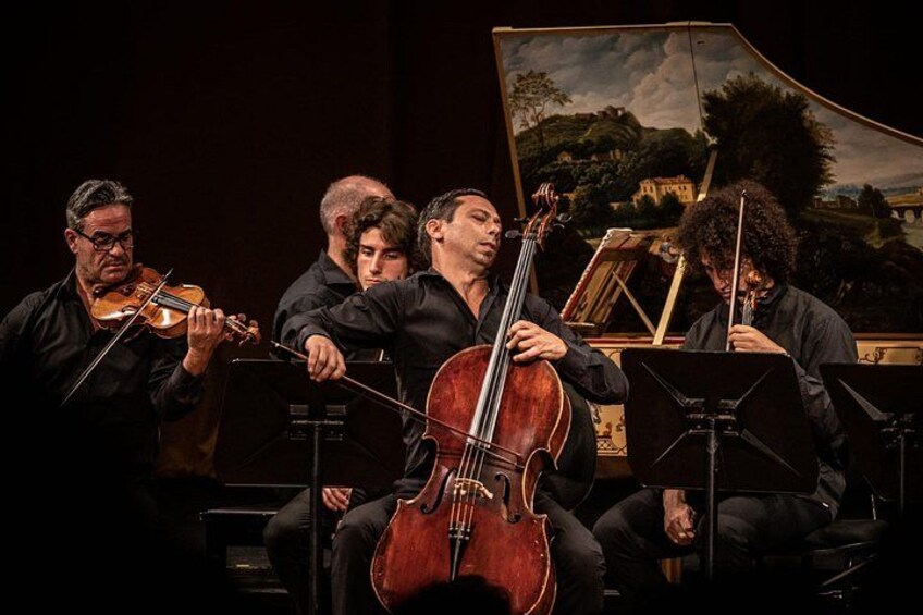A string quartet performing on stage with a backdrop of a landscape painting. 4