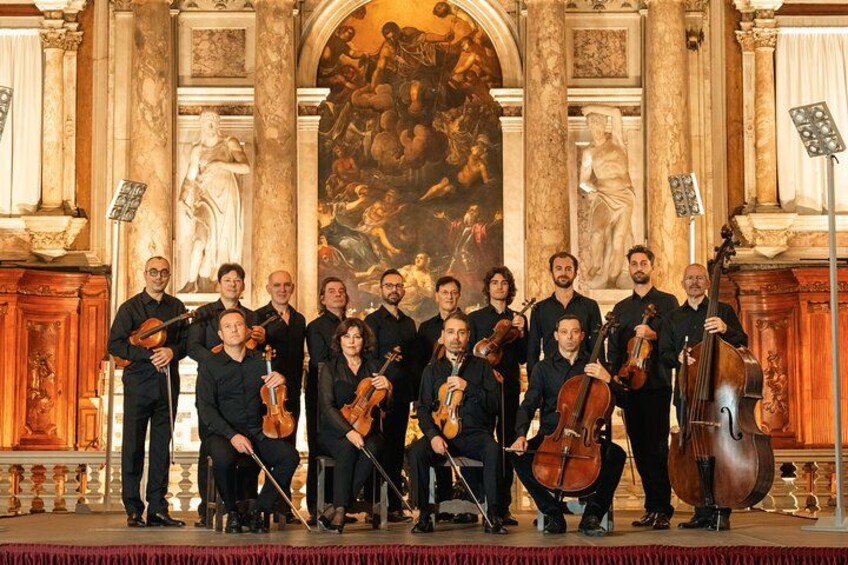 A group of musicians in a classical music setting with ornate architecture and sculptures. 5