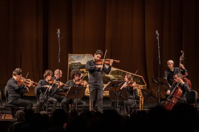 A string quartet performing on stage with a painting in the background. 2
