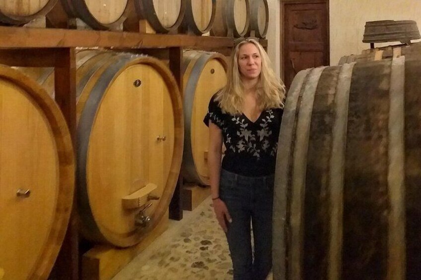 Una persona parada en una bodega con barriles de madera. 1