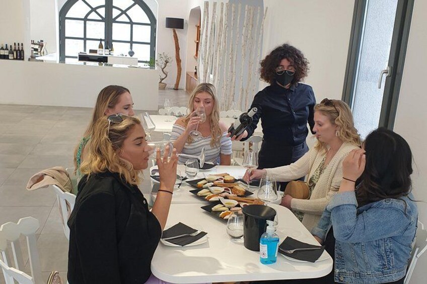 Un grupo de personas sentadas alrededor de una mesa con comida y bebidas, en un espacio interior bien iluminado. 5
