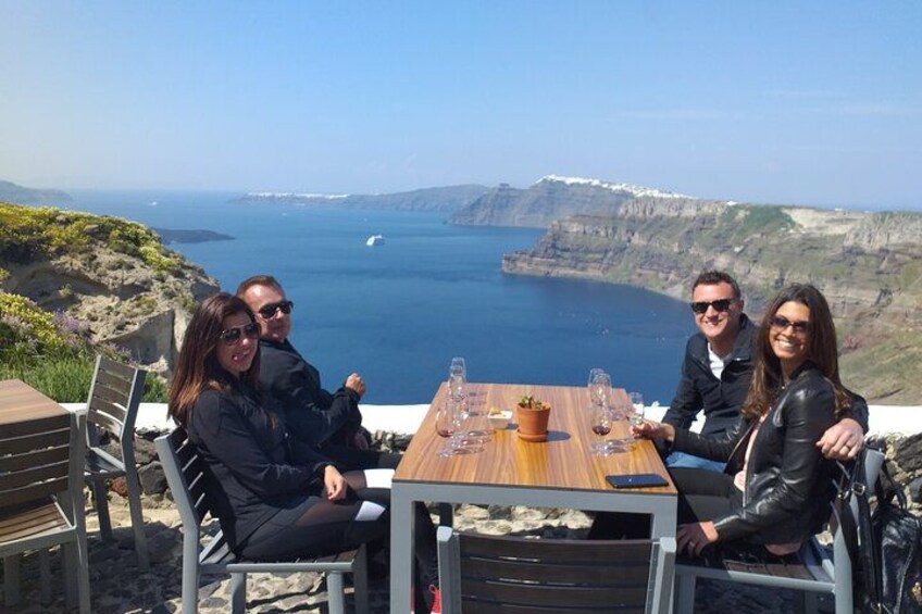 Un grupo de personas sentadas en una mesa con vista al océano y acantilados. 2