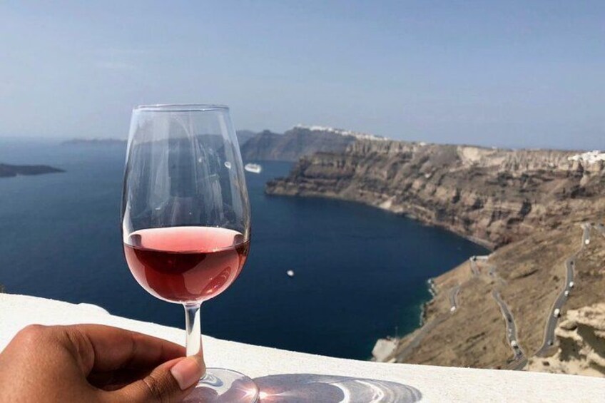 Una mano sosteniendo una copa de vino, con un paisaje costero al fondo. 4