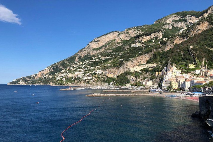 A coastal town with buildings on a hillside, a clear blue sky, and calm sea. 3