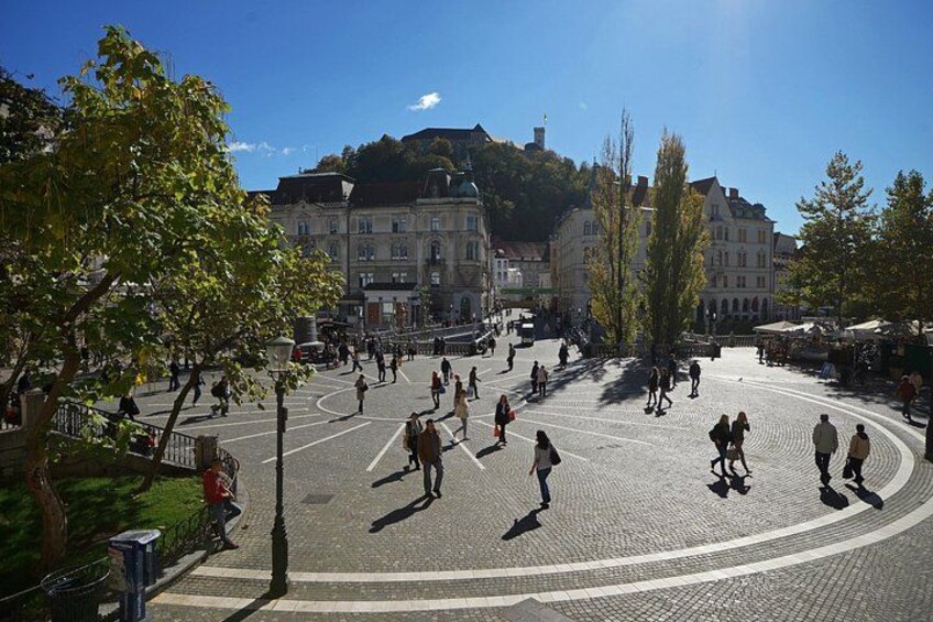 Une place publique où l’on voit des gens se promener, des arbres et des bâtiments historiques. 2