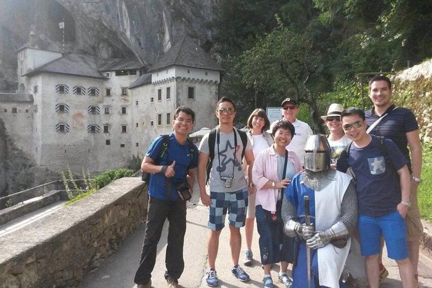 Un groupe de personnes se tient sur un sentier, avec un château en arrière-plan. 2