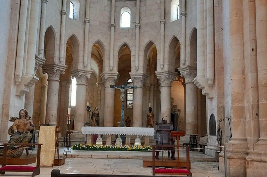 Interior de una catedral con techos altos en arco, un altar central y estatuas. 3