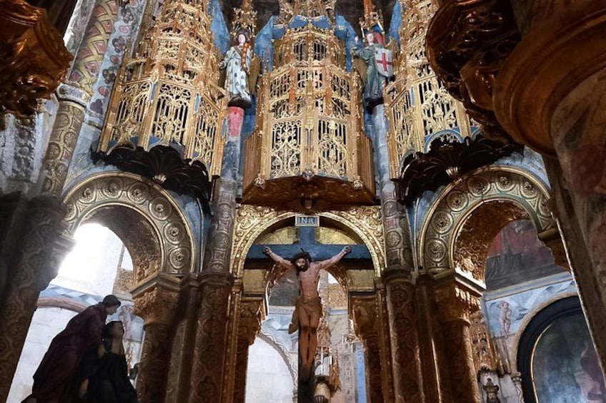 Interior ornamentado de una iglesia con una escena de crucifixión, decoraciones doradas y arquitectura detallada. 5