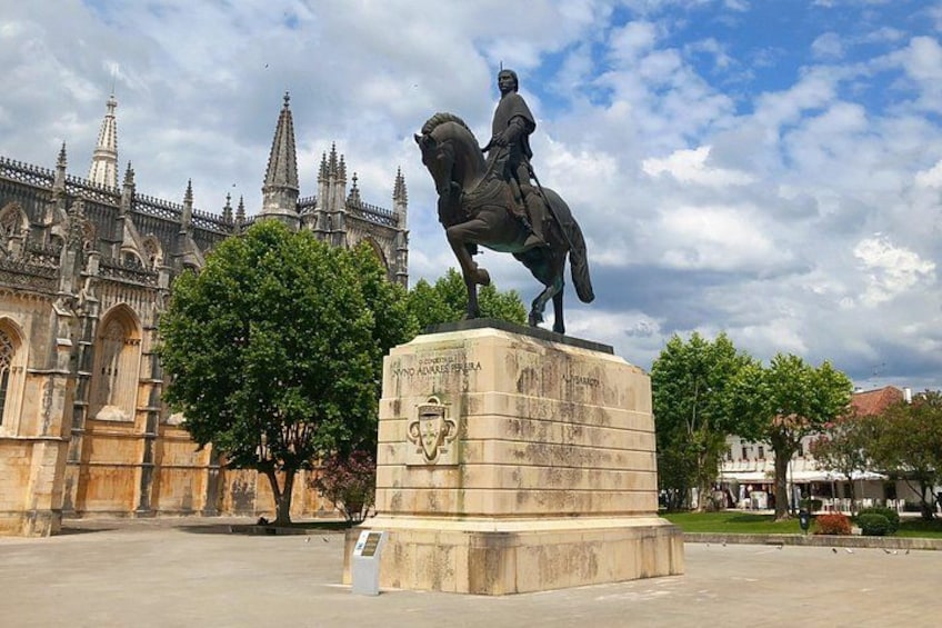 Una estatua de un hombre a caballo frente a un edificio histórico con agujas. 4