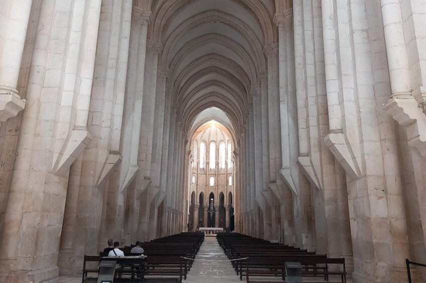 Interior de una catedral con techos altos y abovedados y filas de bancas. 2
