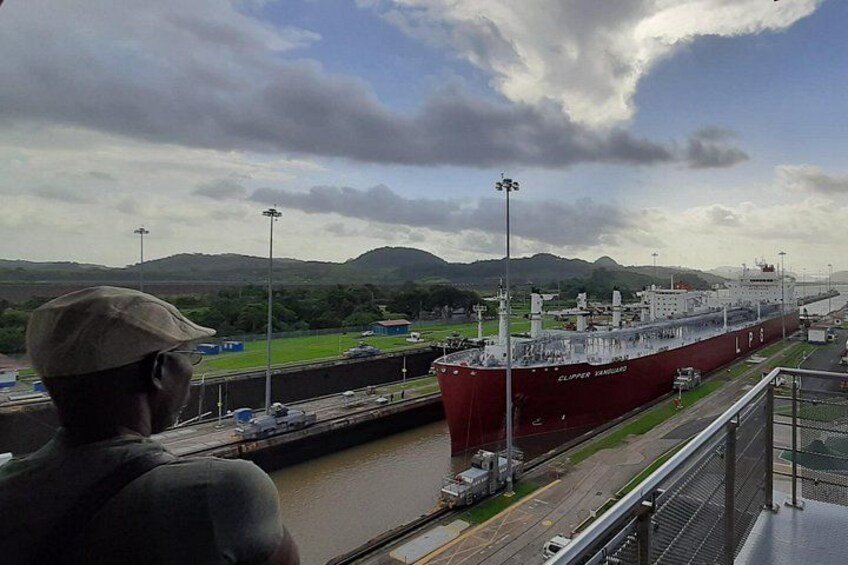 A large red ship docked at a port with a mountainous landscape in the background. 4