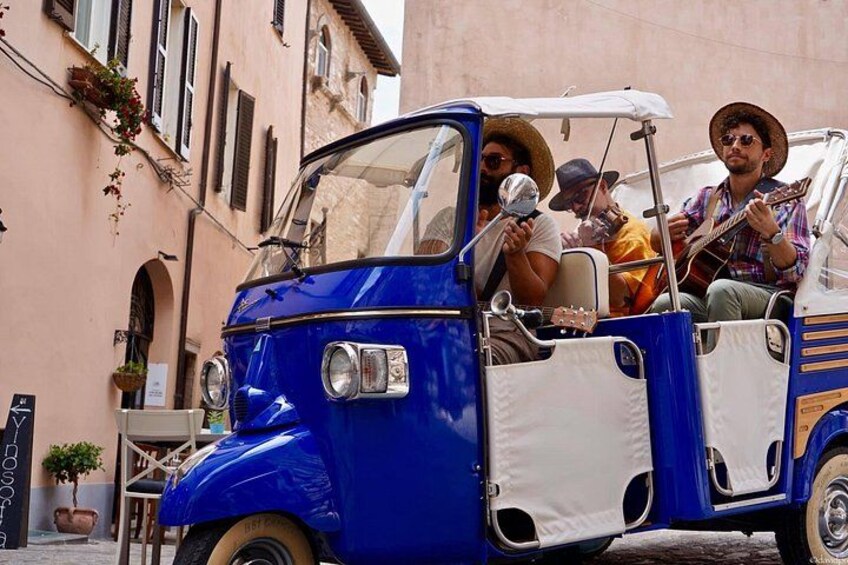 A blue and white vintage car with passengers, parked on a street with buildings. 3