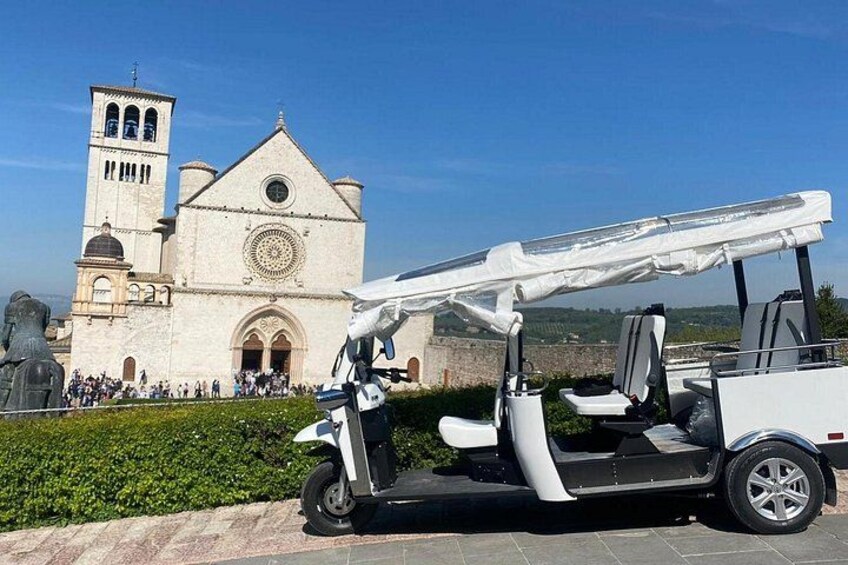 A white golf cart parked in front of a church with a bell tower. 1