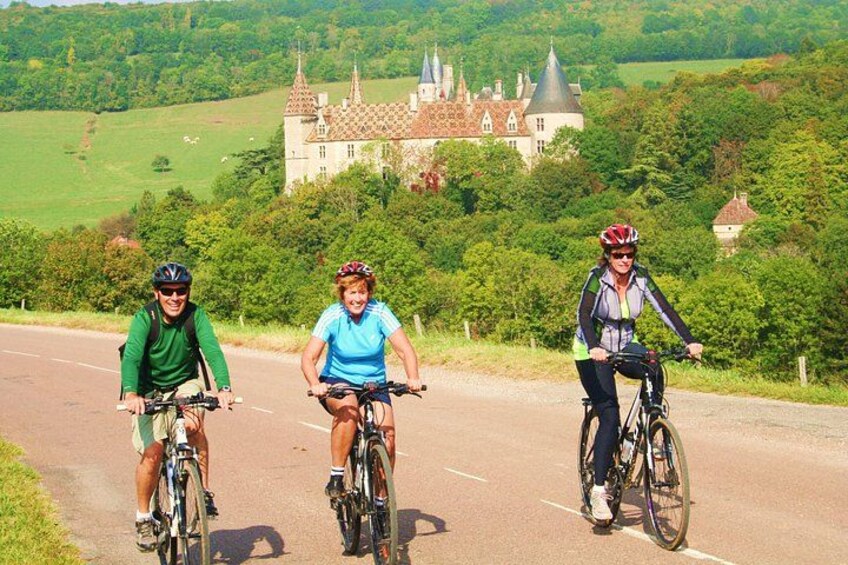Three cyclists on a road with a castle in the background. 4